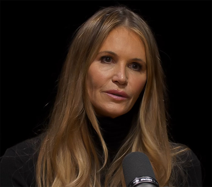 Woman with long hair speaking into a microphone, involved in a discussion about Photoshop use.