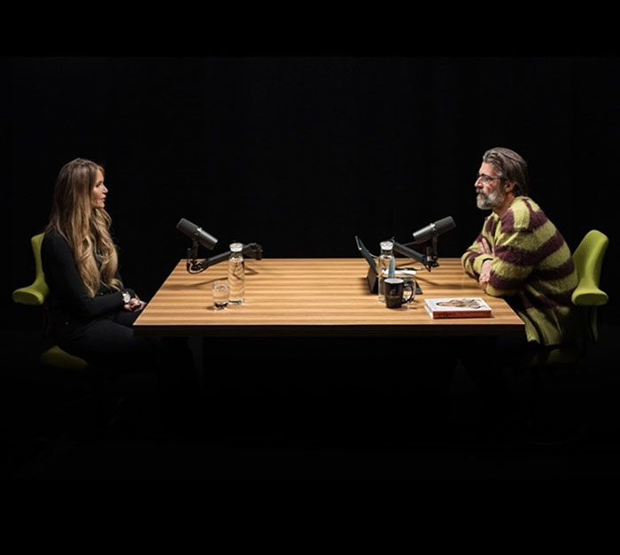 Two people sitting at a table with microphones, discussing Photoshop criticism.