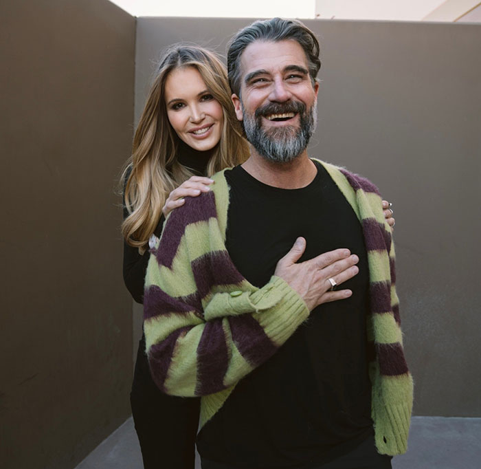 Two smiling individuals, one wearing a striped cardigan, related to Photoshop controversy.