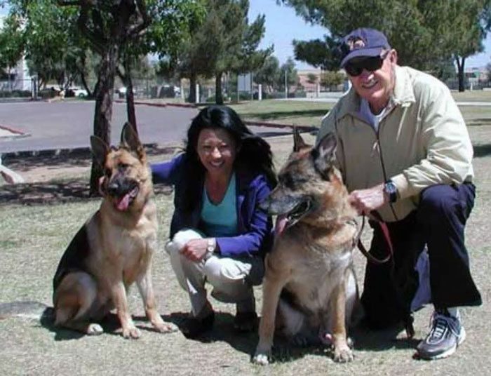 Two German Shepherds with people in a park, related to Gene Hackman investigators' update on dogs that survived.