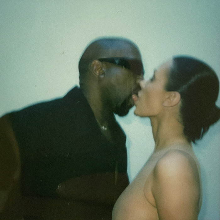 Kanye West and Bianca Censori kissing in front of a plain wall.