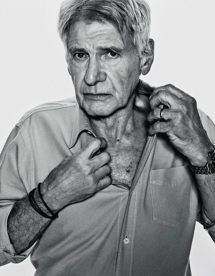 Shirtless grey-haired man in a black-and-white WSJ photoshoot, expressing intensity.