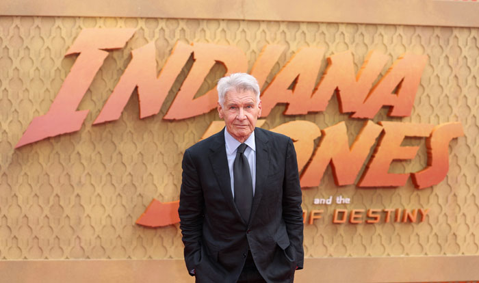 Harrison Ford in a black suit at Indiana Jones event.