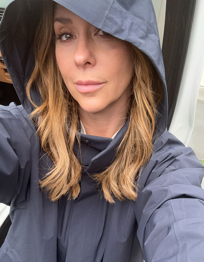 Woman in a hooded jacket taking a bare-faced selfie, highlighting a strong message on aging.