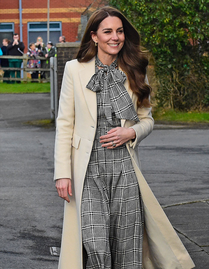 A woman in a stylish coat and patterned outfit, embodying fashion policy defended by Kensington Palace.