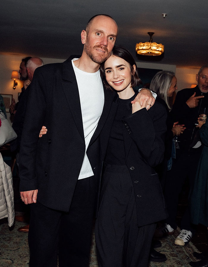 Couple posing together in a formal setting, dressed in matching black outfits.