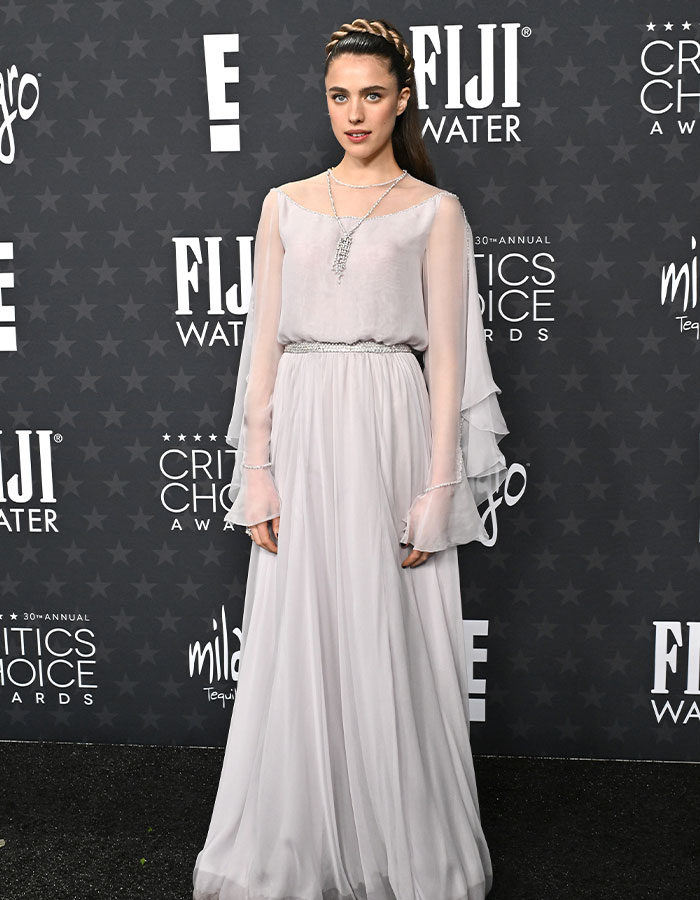 A person in a light gown poses at the Critics Choice Awards red carpet, embodying daring outfits.