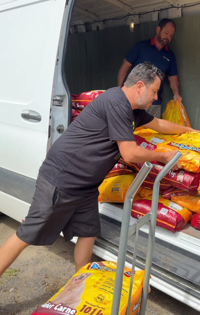 Man unloading dog food from a van, dedicated to feeding stray dogs for 25 years.