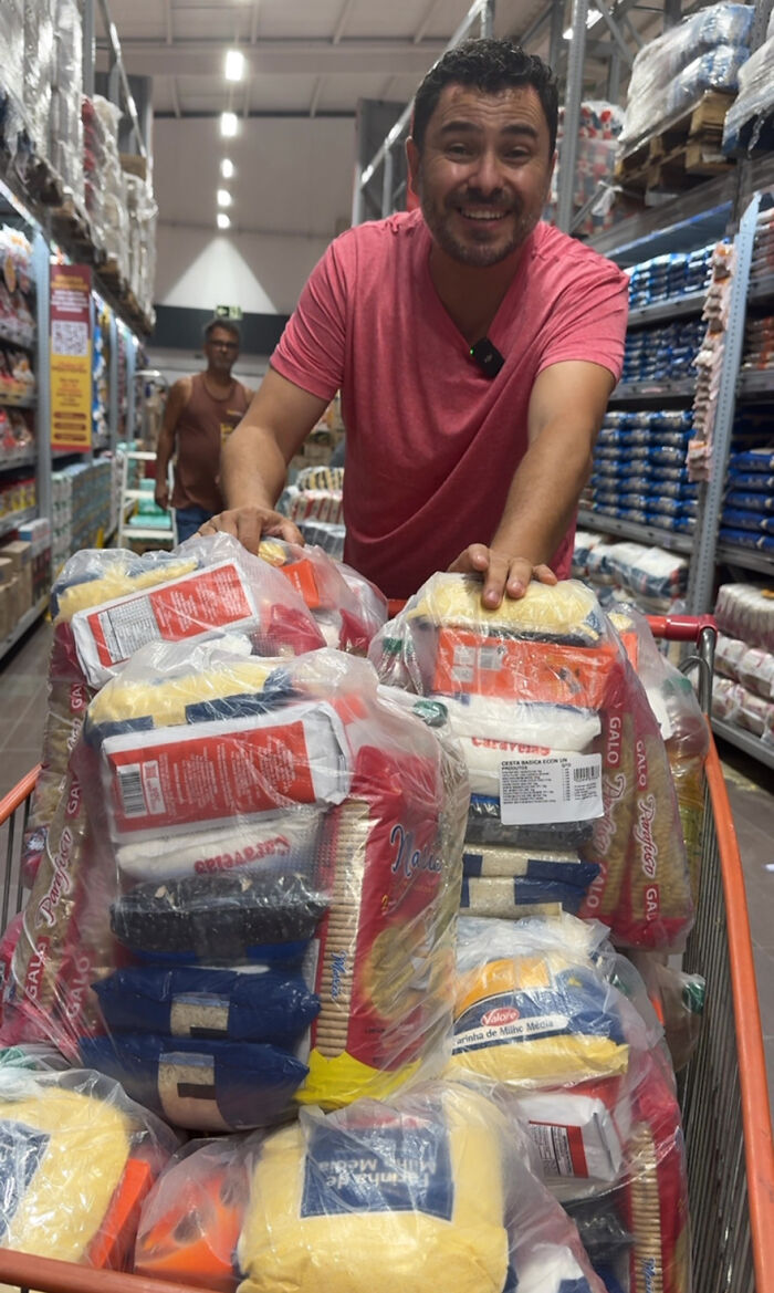 Man smiling, pushing a cart of food supplies, dedicated to feeding stray dogs for 25 years.