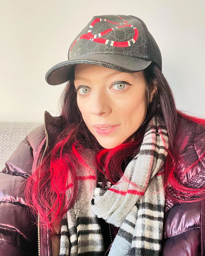 Person in a black cap and plaid scarf, with red highlights, presents a confident expression; theme relates to fan interactions.