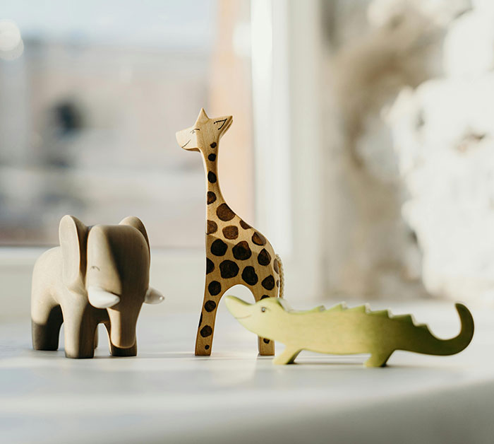 Wooden animal toys, including an elephant and giraffe, symbolize birthday party demands discussion.