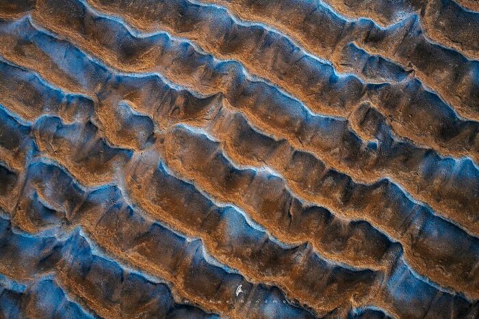 Aerial shot of brown and blue textures in a natural landscape by Michael Hindman.