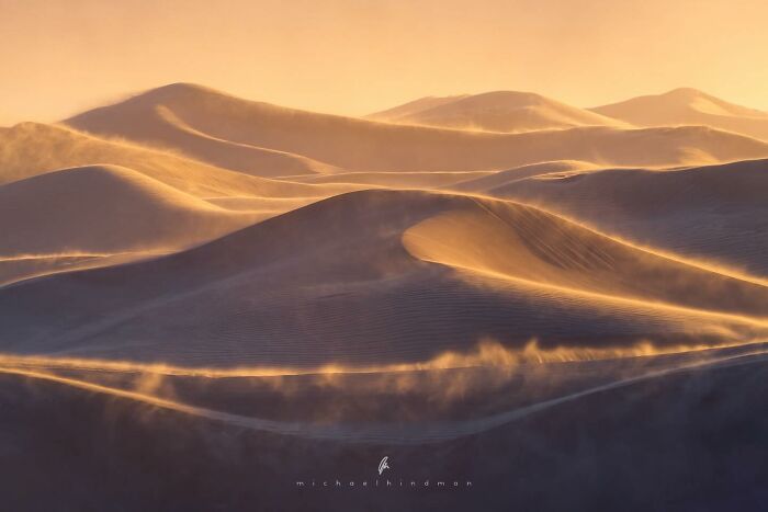 Golden sand dunes at sunset, showcasing textures of nature with soft light and shadows.