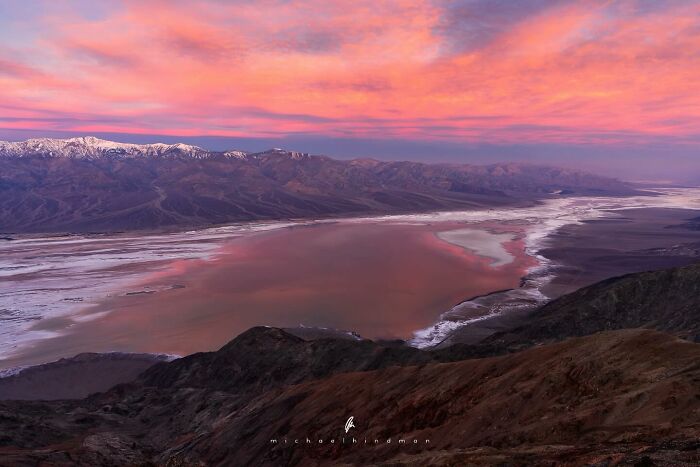 Intimate landscape photo by Michael Hindman of a sunset over vast, textured desert terrain with snow-capped mountains.