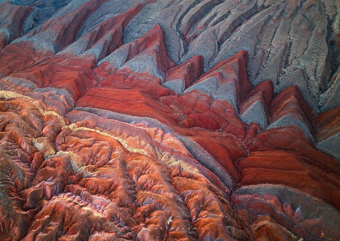 Intimate landscape photo by Michael Hindman showcasing vibrant, textured layers of red and gray earth formations.