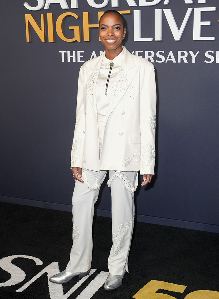 Person in a white embellished suit and silver shoes at SNL 50th Anniversary, highlighting wacky red carpet fashion choices.