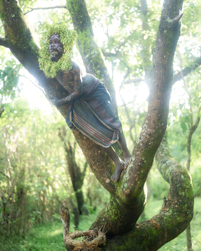 Ethiopian person adorned with foliage sitting in a tree, captured by Daniel Kordan.