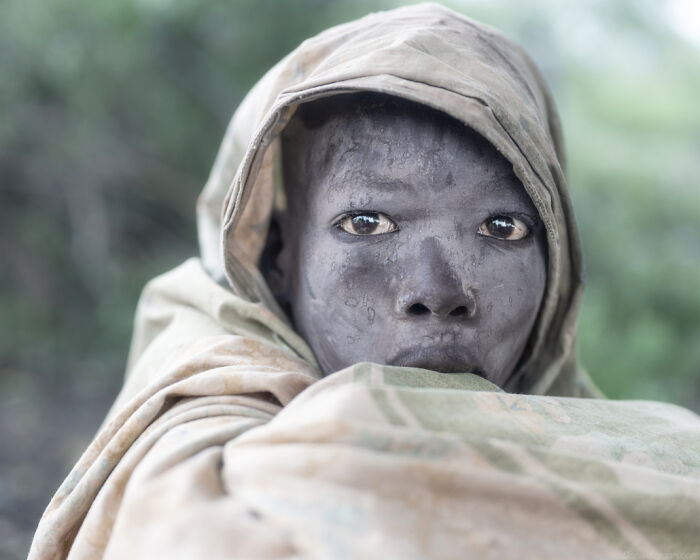 Ethiopian person wrapped in fabric, gazing intensely; part of a captivating photography series by Daniel Kordan.