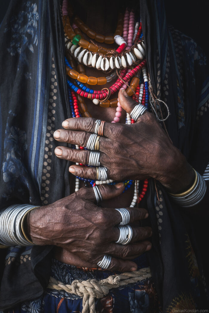 Ethiopian person adorned with colorful necklaces and rings.