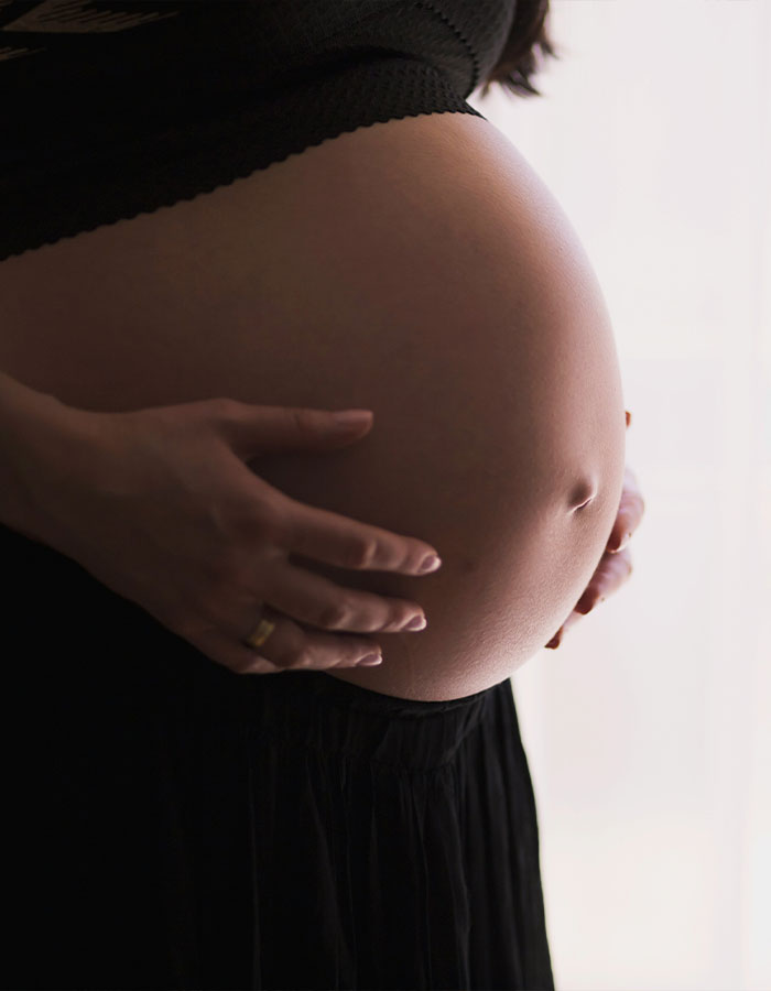 Pregnant woman holding her belly, symbolizing surrogacy and motherhood.