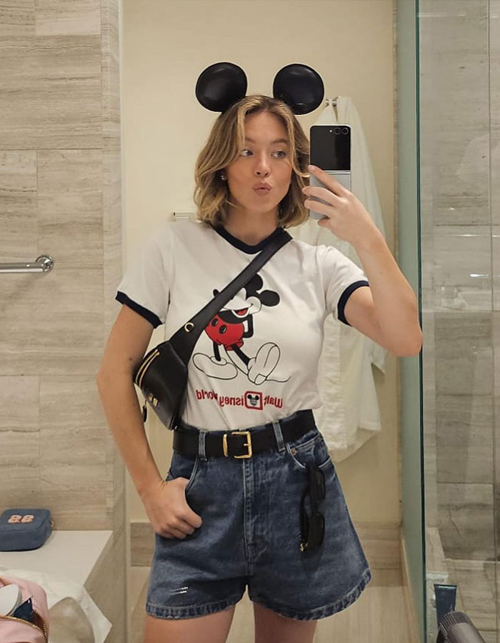 Person taking a mirror selfie wearing Mickey Mouse ears and a themed shirt.