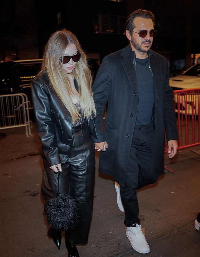 Couple in fashionable black attire walking, related to Sydney Sweeney and fiancé postponing their wedding.