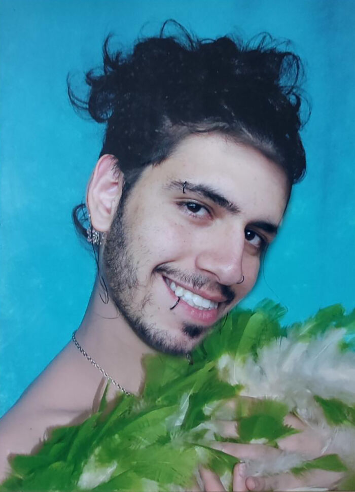 Smiling man holding green feathers, playing a funny prank that made people laugh a lot online.