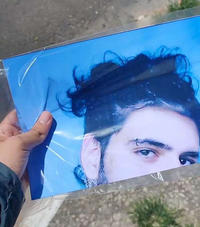 A person holding a printed photo close-up as part of a funny prank on their family.