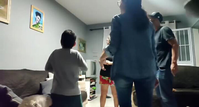 Family laughing in a living room during a prank, featuring playful interactions and a cozy atmosphere.