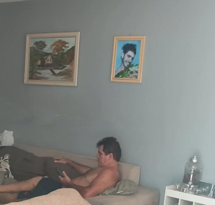 Man sitting on a couch, surrounded by art, involved in a funny prank on his family.