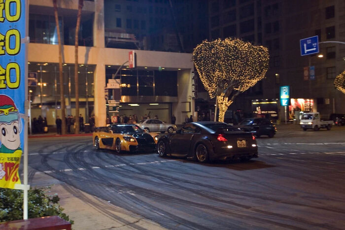 Two sports cars drift on a city street at night, showcasing random world events.