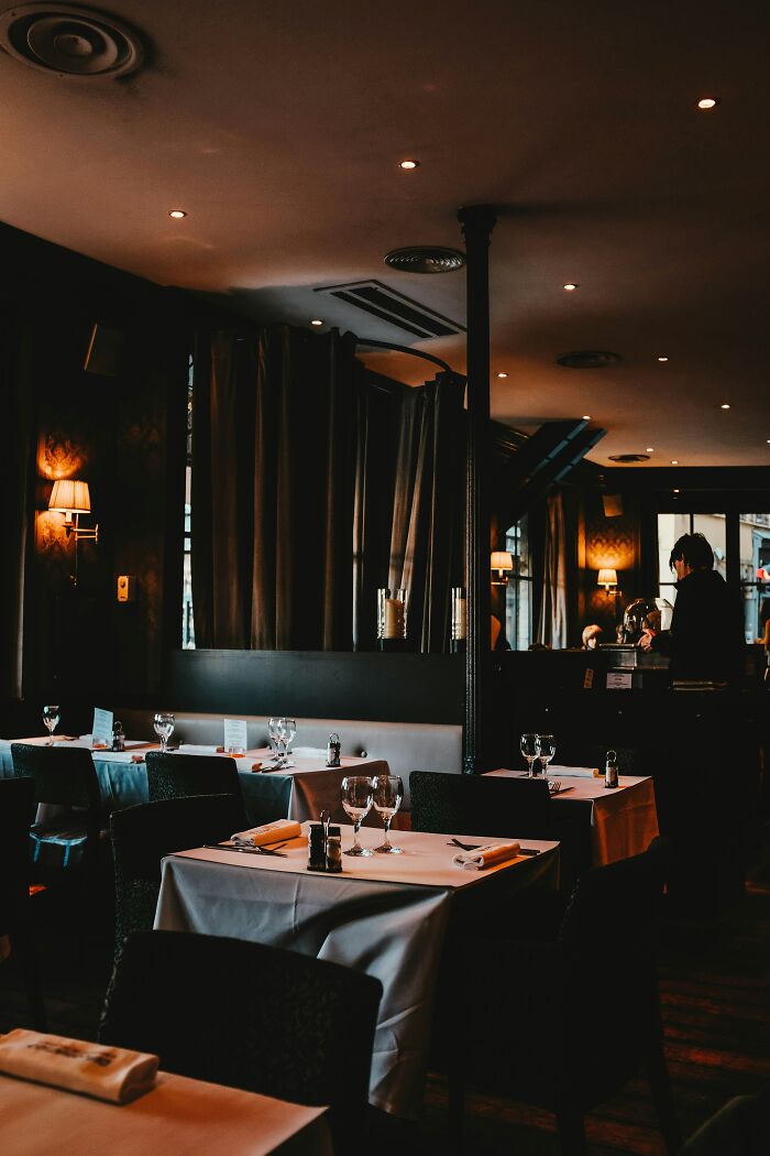 Dimly lit restaurant interior with set tables, reflecting a Gen Z complaint environment.