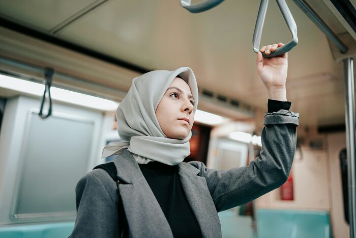 Individual in transit, holding a subway handrail, embodies modern travel essentials.