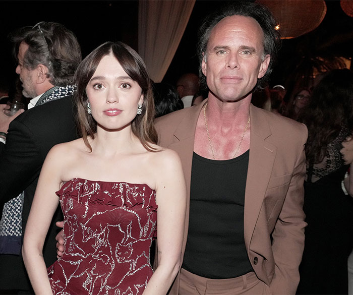 Young woman in a red strapless dress and a man in a tan suit at a formal event, related to intimacy coordinators debate.