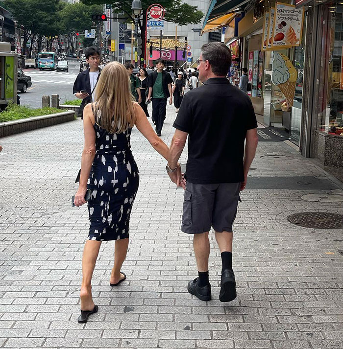 A couple holding hands walking on a busy city street; focus on Bianca Censori's mom.