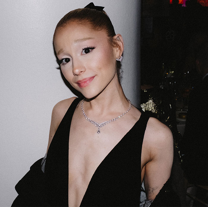 Ariana Grande in a black dress with a diamond necklace poses at an event, sparking concern for her thin appearance.