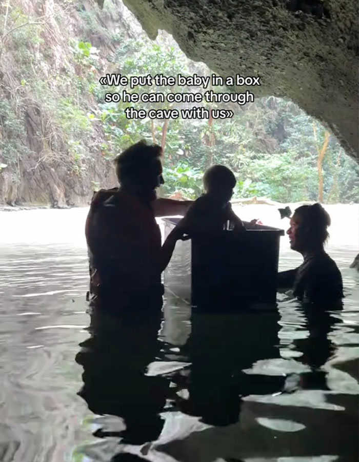 Parents with baby in a plastic box in a cave in Thailand, creating controversy.