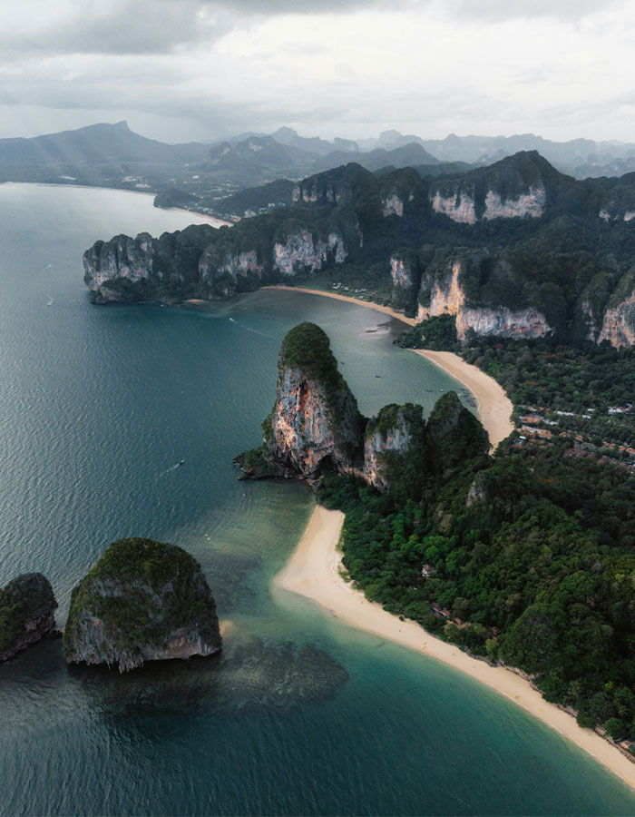 Aerial view of scenic beach and cliffs in Thailand, surrounded by turquoise waters.