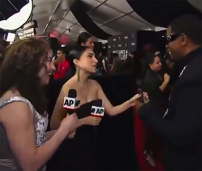 Reporters interviewing a person at the Grammys event.