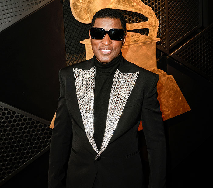 R&B legend in a black and silver outfit wearing sunglasses at the Grammys.