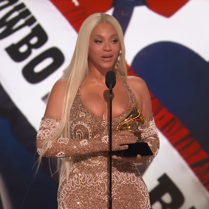 Beyoncé in glittering dress holds Grammy on stage, wardrobe malfunction noted during the event.