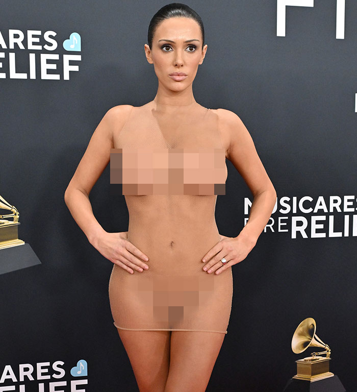 Woman in a sheer dress at a red carpet event, posing confidently, related to Bianca Censori designer experience.