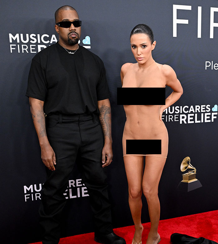 Bianca Censori in a revealing dress at the Grammys alongside a man in black, amid controversy.