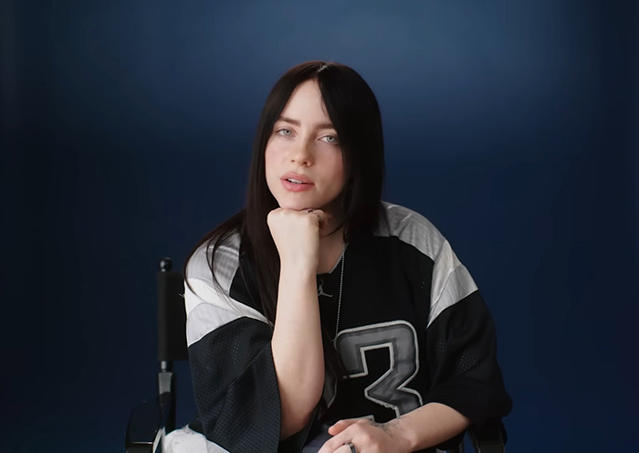 Person in a black sports jersey with the number three, sitting in front of a dark blue background.