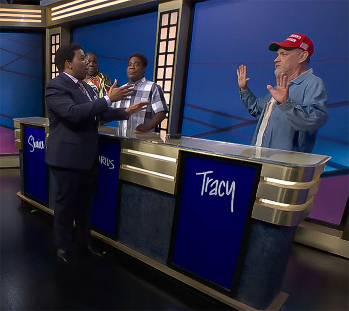 Actor in a red MAGA hat gestures during a game show skit on SNL.