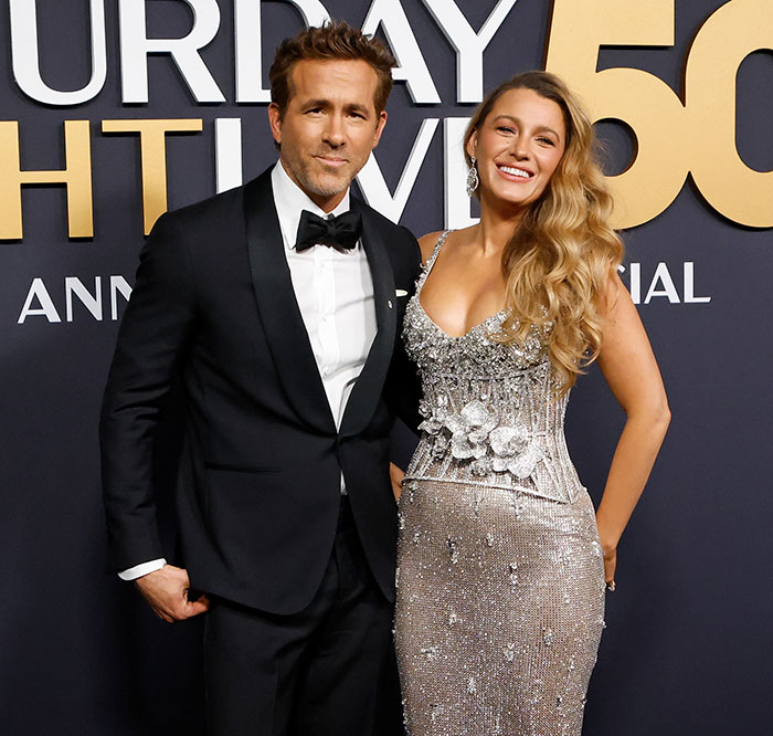 Blake Lively and Ryan Reynolds in elegant attire at SNL 50 event backdrop.