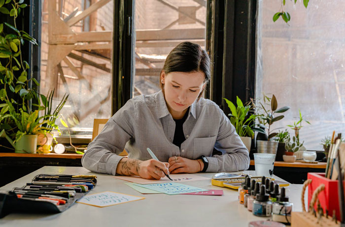 Woman writing at a desk, surrounded by plants, illustrating a story about a bridezilla seeking refunds.