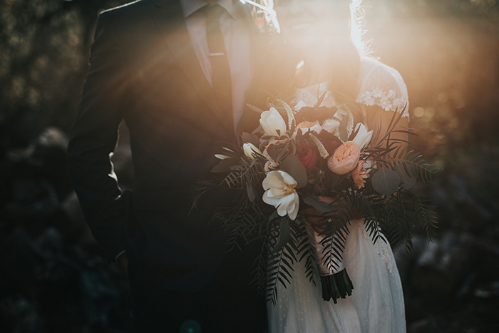 Couple in sunlight, woman holding bouquet, related to wedding and white dress etiquette.