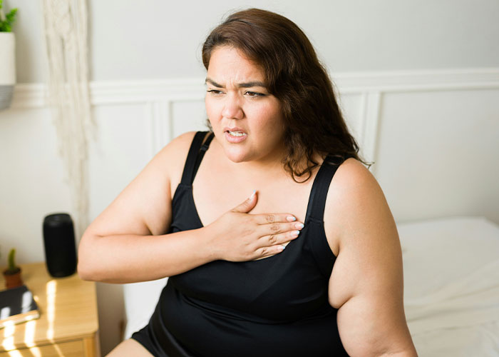 Woman expressing concern, touching her chest, representing health and weight conflict.