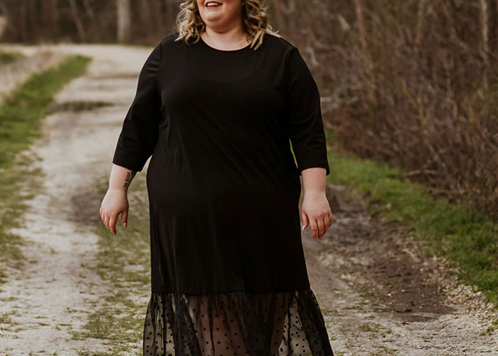 Person in a black dress walking on a dirt path, related to conflict over health and weight during a girls' night.